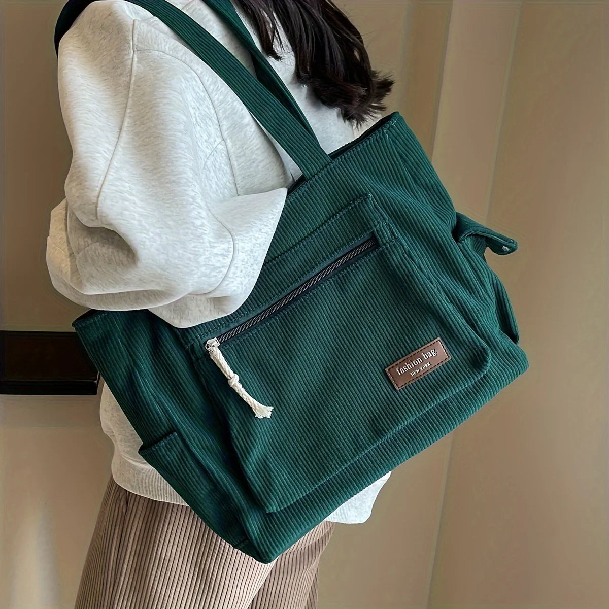 Green textured bag with a brand label worn by a person against a neutral background