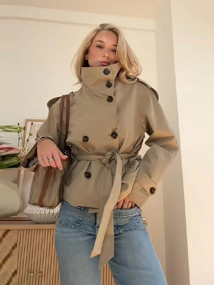 Woman wearing a beige trench coat with a white wall background